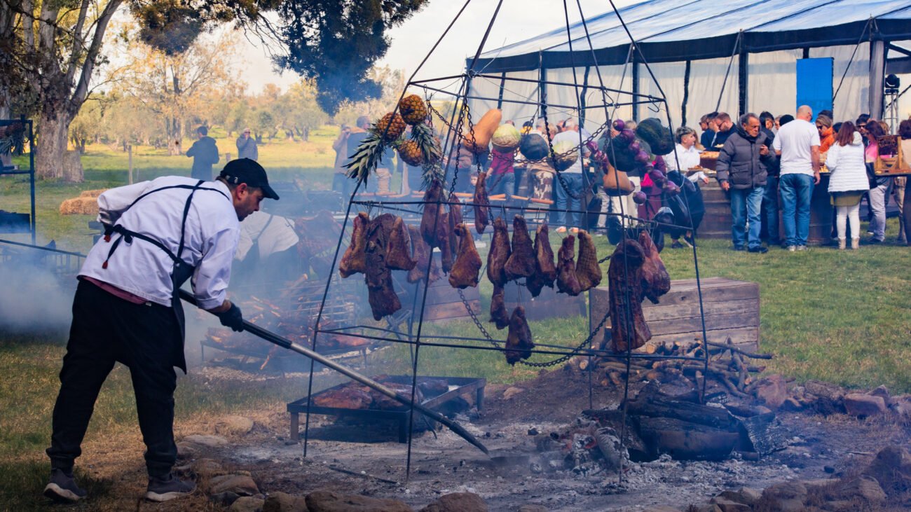 Cocinero preparando carnes y vegetales al fuego durante un evento en la bodega