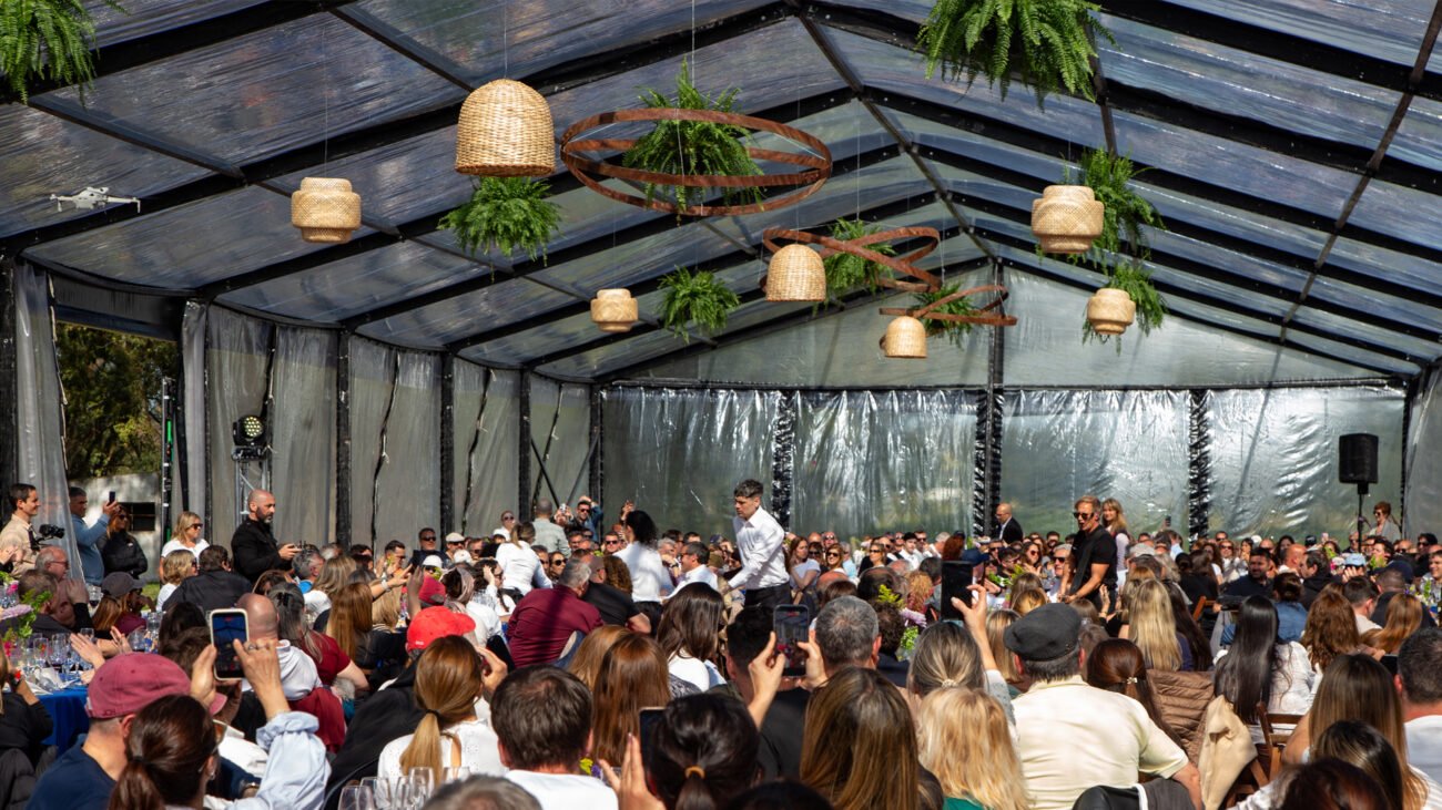 Invitados reunidos en una carpa con mesas y ambientación colgante